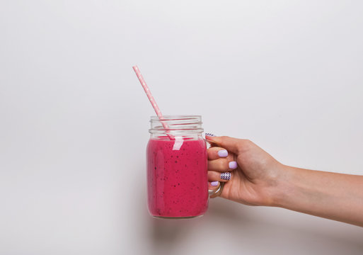 Woman's hand holding a glass jar with berry smoothie