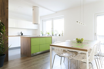 Fototapeta na wymiar Modern and design scandinavian kitchen with plants, kitchen table and accessories . Sunny and bright space with white wall.