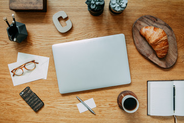 Stylish and modern composition of wooden desk with laptop, phone, shoes notebook, glasses and office accessories. Creative desk of traveler.