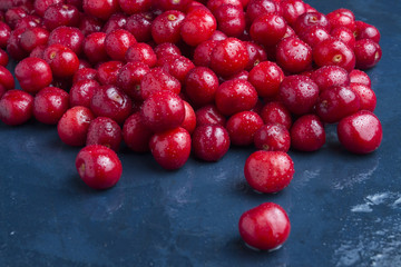 Freshly picked cherries with drops of dew and water on a dark blue stone background. The concept of harvesting. Flat lay, top view