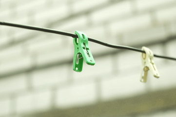 Two clothespins on a rope on the background of a brick wall of house. Selective focus