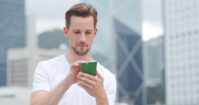 Fototapeta Caucasian young man use of mobile phone for text message