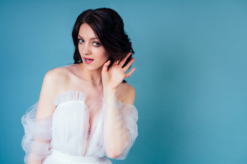 Indian woman in a wedding dress ieavesdrops and gossips on a blue background in the studio