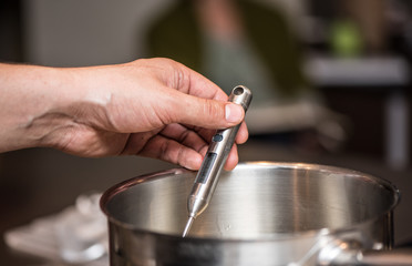 Chef's hand measuring temperature with digital thermometer