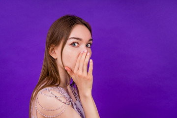 woman in dress ieavesdrops and gossips on a violet background in the studio
