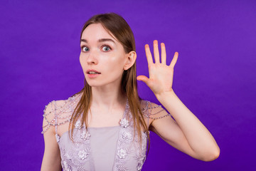 woman in dress ieavesdrops and gossips on a violet background in the studio