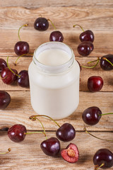 Greek yoghurt, opened cherry with a ossicle, on a cherryes and brown wooden background