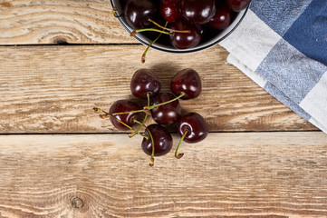 Cherries in a white bowl next to a doily and a few cherries in front, on a wooden background, flat...
