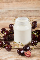 Greek yoghurt, opened cherry with a ossicle, on a cherryes and brown wooden background