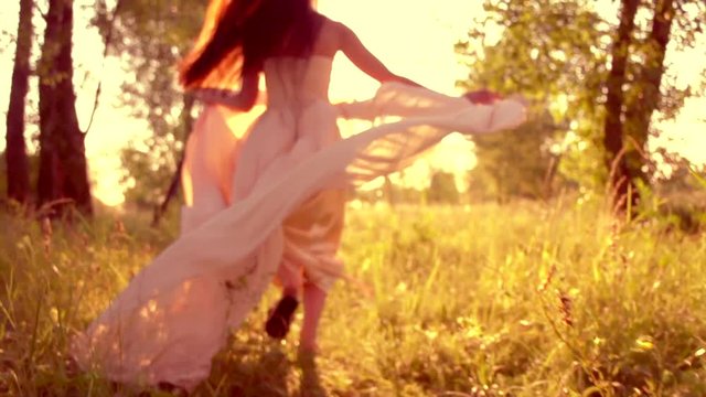 Beauty romantic young woman in long chiffon dress with gown running in the forest on sunset. Slow motion 240 fps. 4K UHD video 3840x2160