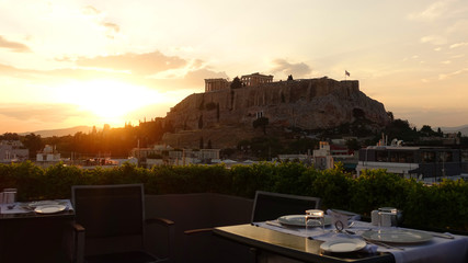 Iconic Acropolis hill and the Parthenon as seen from rooftop at sunset with golden colours and beautiful cloud formations, Athens historic center, Attica, Greece     