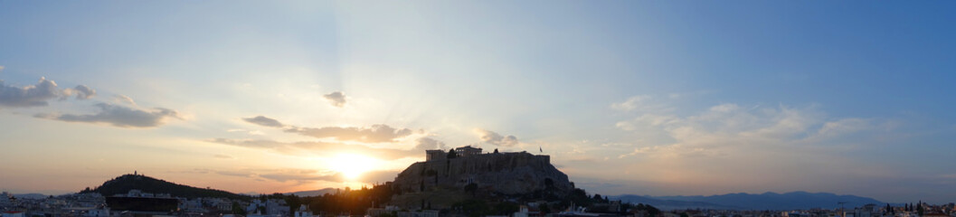 Iconic Acropolis hill and the Parthenon as seen from rooftop at sunset with golden colours and...