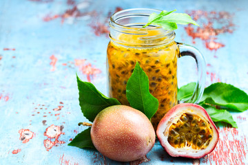 Passion fruit in a glass jar with whole and half fruit on blue wooden table