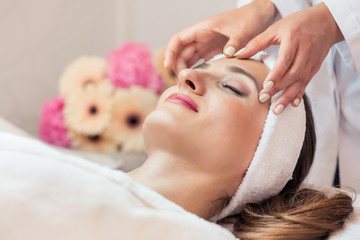 Close-up of the face of a beautiful woman relaxing under the gentle touch of the therapist, during...