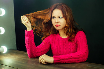 unhappy woman sits in a beauty salon in front of a mirror and looks at bad hair . The concept of...