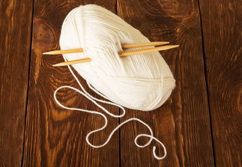 Hank of soft yarn and wooden knitting needles, on table