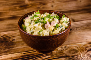 Ceramic bowl with russian traditional salad olivier on wooden table