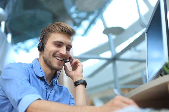 Smiling friendly handsome young male call centre operator.