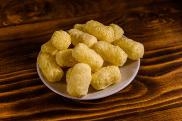 Ceramic plate with corn sticks on wooden table