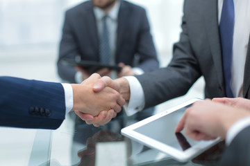 Men shaking hands with smile at office with their coworkers.