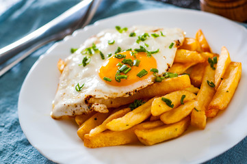 fried egg with potato in a white plate on table