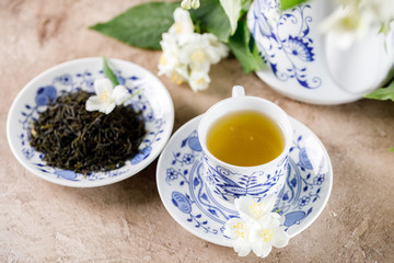Obraz na płótnie Canvas A cup of green tea with a taste of jasmine and a saucer with dry leaves of tea.