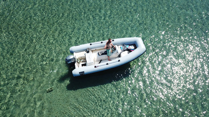 Aerial photo of small inflatable speed boat in turquoise clear tropical waters