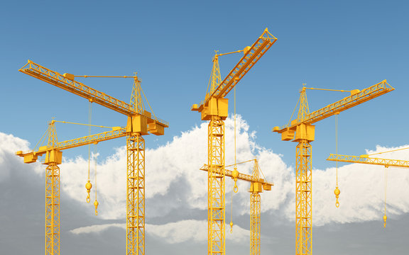 Construction cranes against a blue sky with clouds