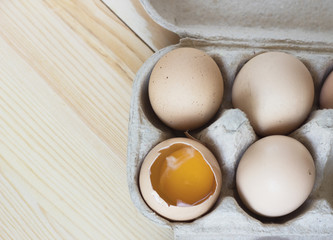 Close-up view of raw chicken eggs in an egg box on wooden background