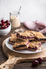 Homemade crumble bars with cherries on rustic wooden background, copy space