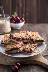 Homemade crumble bars with cherries on rustic wooden background, copy space