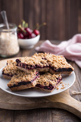 Homemade crumble bars with cherries on rustic wooden background, copy space