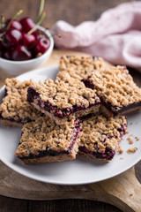 Homemade crumble bars with cherries on rustic wooden background, copy space