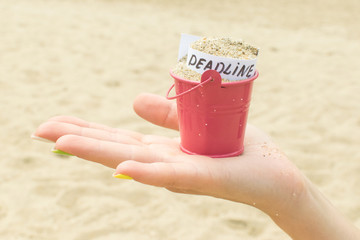 Deadline concept. The inscription in a bucket with sand on a woman's hand.