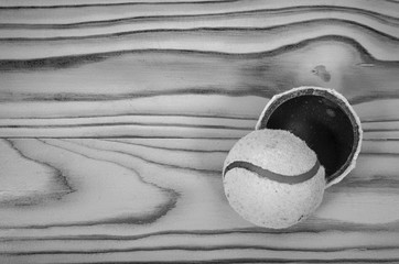 Torn tennis ball on a wooden table.