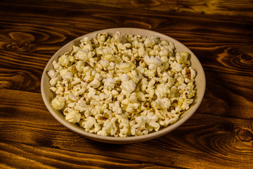 Ceramic plate with popcorn on wooden table