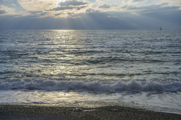 fragment of the  stony beach of the beach with a mobile sea wave against a beautiful sunset