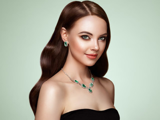 Brunette Girl with Long Healthy and Shiny Curly Hair. Care and Beauty. Beautiful Model Woman with Wavy Hairstyle. Make-Up and Jewelry