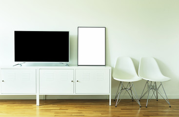 wide screen TV on white stand near light wall.Poster on table in room.