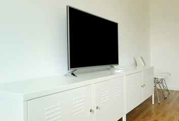 wide screen TV on white stand near light wall. living room