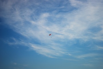 Paraglider flies in the blue sky with white clouds