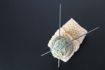 A ball of wool with knitting needles and socks on a gray table. Needlework.