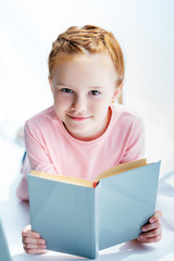 adorable child holding book and smiling at camera