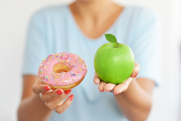 The best choice for a healthy lifestyle, between sweet and attractive doughnut and fresh green apple fruit
