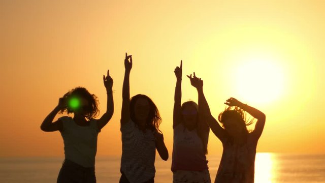 Dancing woman party at beach sunset. Playful girls silhouettes on summer sunset. Enjoy summertime at summer party. Woman have fun with hands up at sun set. Jumping woman silhouettes