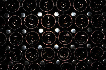 Many old glass dusty champagne bottles, stacked in the wine cellar close up