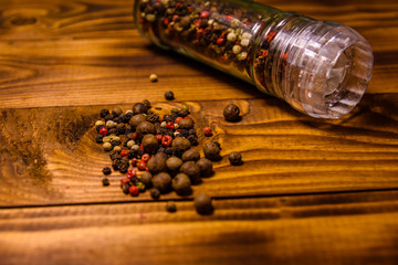 Pepper mill and scattered spices on the wooden table