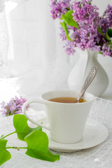 cup of tea on a light table near a window in the morning and bunches of flowers with a copy space