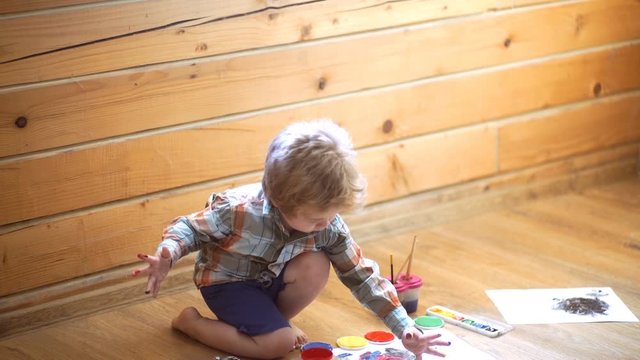 Talented boy draws a yellow paint in children's center in master class of art. Creative kid boy. Child fingerprint art. Drawing for children, little artists. Finger paints, free time for toddler
