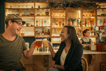 Two smiling young friends cheering with drinks in a bar 
